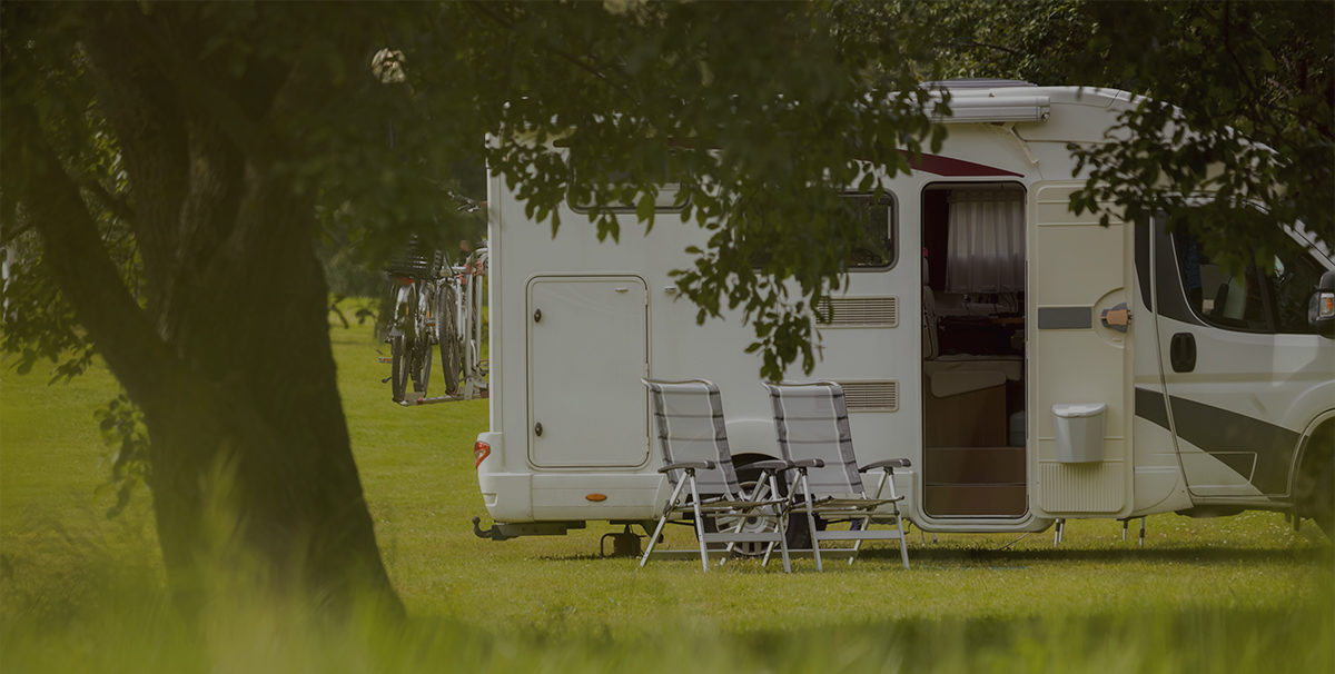Camping-car garé sur un emplacement ombragé au bord d’une allée de camping